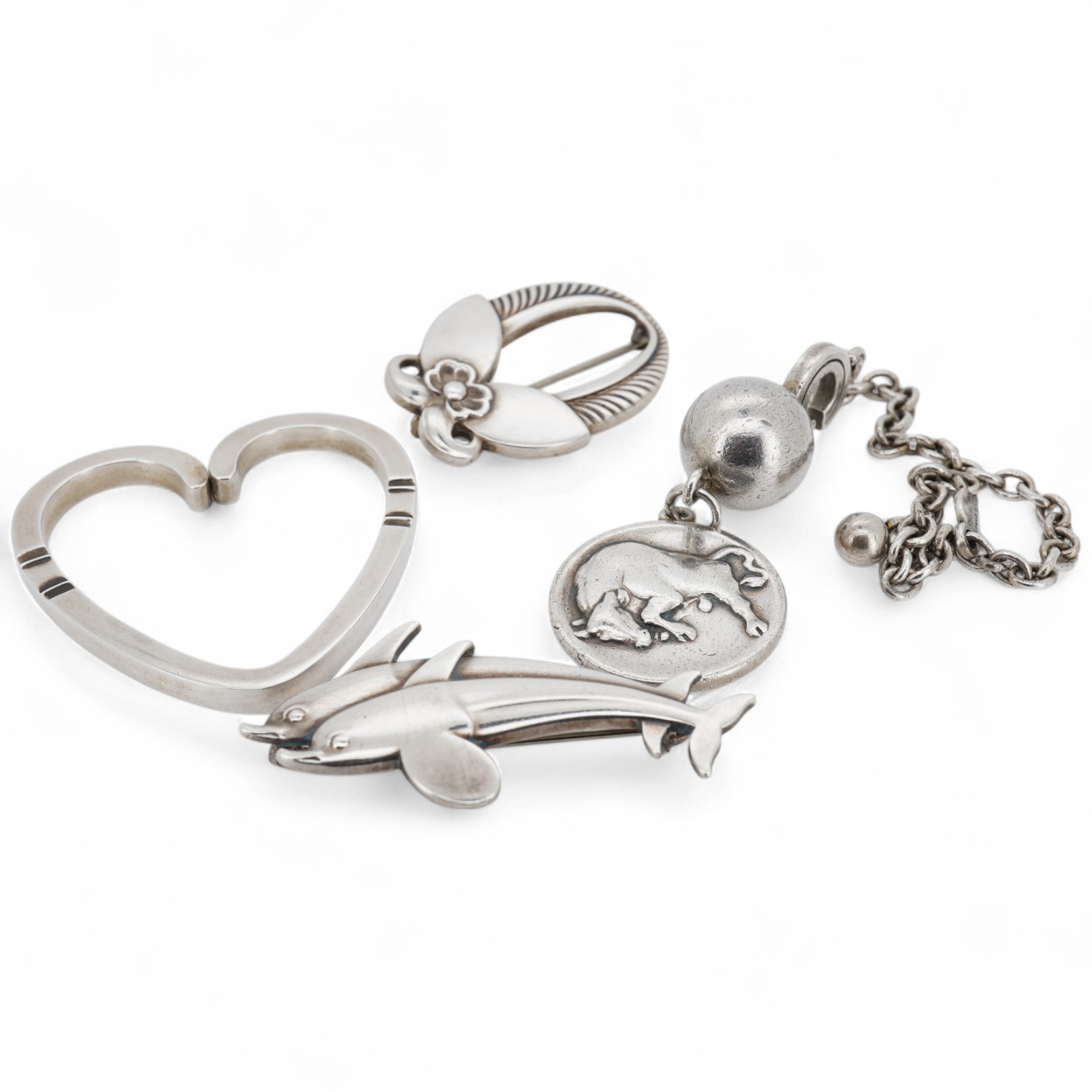 A Danish Georg Jensen sterling twin dolphin brooch, 40mm and a similar flower brooch, design numbers 317 and 227, a 1960's Georg Jensen silver bracelet, design no.46 and a similar 1970's silver heart pendant, design no.4